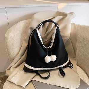 Détail du sac cabas noir avec bordure en fausse fourrure blanche et pompons décoratifs