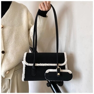 Detail of black suede tote bag with white shearling trim and mini hanging pouch charm