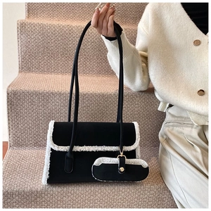 Detail of black wool underarm bag featuring white plush faux fur trim and accessory pouch
