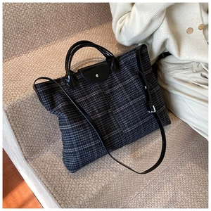 Close-up of quilted tweed tote bag with black leather handle and silver metal snap button