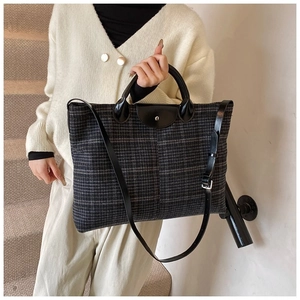 Detail of checkered tote bag showing leather handles and textured fabric finish
