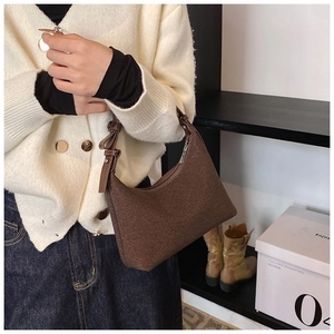 Dettaglio di una borsa sottobraccio in pile marrone con cerniera e texture opaca