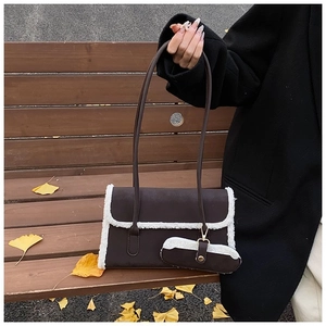 Detail of dark brown faux suede shoulder bag with white fleece trim in autumn setting