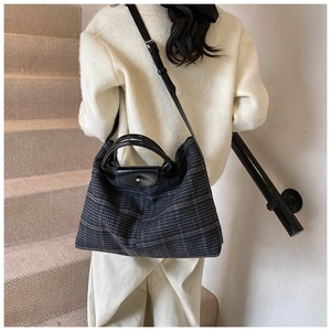 Detail of dark grey quilted tote bag with black leather flap and silver snap button closure