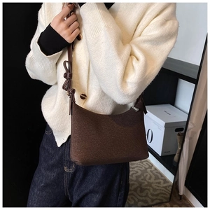 Elegante borsa a spalla marrone scuro con fiocco decorativo sulla tracolla indossata da modella