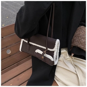 Detail of dark brown faux leather shoulder bag with white faux shearling trim and gold hardware