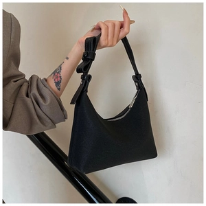 Dettaglio della borsa hobo nera con un nodo decorativo sulla tracolla della borsa