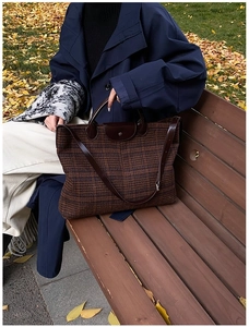 Brown plaid tote bag with leather handles and strap shown in a scenic autumn park setting
