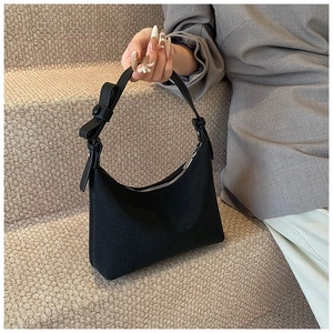 Dettaglio borsa hobo nera con trama in nylon, tracolla regolabile e fiocco decorativo
