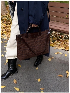 Detailed view of brown quilted tote bag with leather handles in autumn park setting