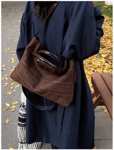 Brown plaid tote bag with dark leather trim shown on a model in an autumn outdoor park