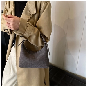Dettaglio borsa hobo in lana grigia con cerniera portata da una modella in trench coat