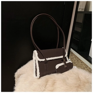 Close-up of retro brown shoulder bag with white faux fur trim on plush rug background