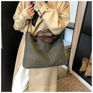 Detail shot of a quilted tote bag with leather flap handle and slim shoulder strap