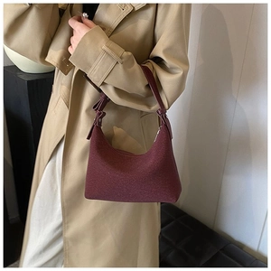 Dettaglio della borsa hobo a mezzaluna bordeaux in lana operata su un trench kaki
