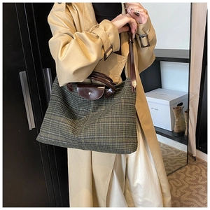 Detailed view of dark green quilted tote bag with brown leather flap and handles