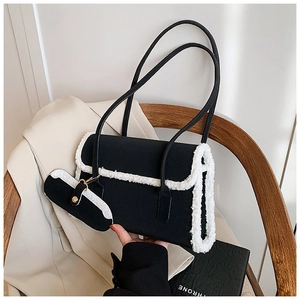 Close-up of black crossbody bag with white faux shearling trim and mini pouch
