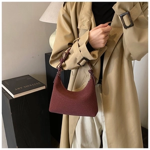 Dettaglio della borsa hobo bordeaux testurizzata con tracolla a nodo e trench classico