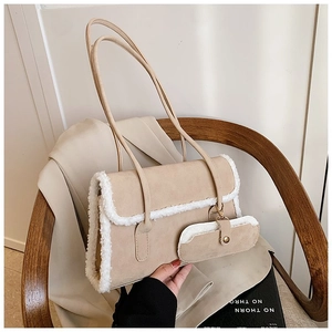Chic beige suede shoulder bag with plush shearling trim and matching coin purse on a chair