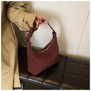 Dettaglio della borsa a spalla in feltro rosso scuro con fiocco decorativo e tessuto