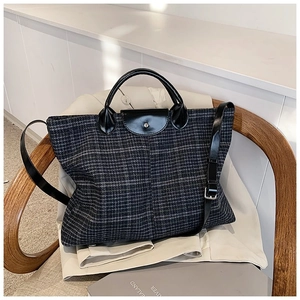 Detail of grey plaid tote bag featuring black leather handles and silver metal hardware
