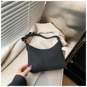Dettaglio di una borsa sottobraccio nera a mezzaluna con fiocco laterale e finitura opaca