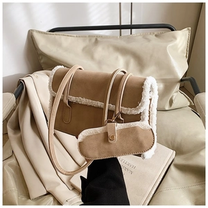 Detailed view of brown suede shoulder bag with plush shearling trim and mini pouch charm