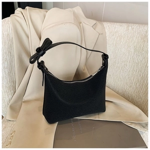 Dettaglio di una borsa a tracolla nera con un fiocco decorativo sulla tracolla