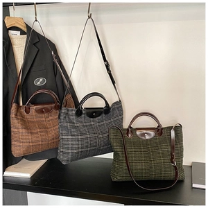 Close-up of quilted tote bags in brown, green and grey with leather trim and gold snap
