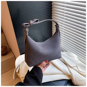 Borsa a mezzaluna in feltro grigio con fiocco decorativo su sfondo di abito casual
