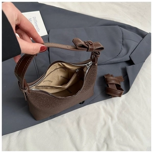 Dettaglio interno della borsa in pelle marrone con tasca zip e fiocco decorativo