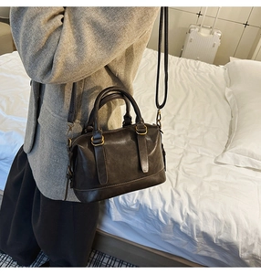 Detail of a dark brown Boston bowling bag featuring adjustable straps and gold-tone hardware