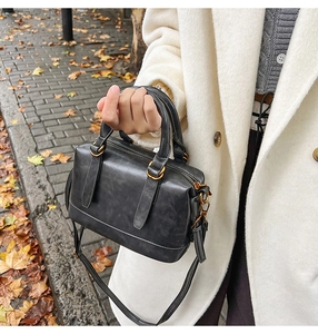 Close-up of black retro leather bowling bag with gold hardware and stylish handle