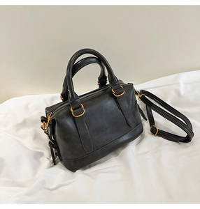 Close-up of black Boston bag showing gold hardware and adjustable shoulder strap