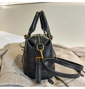 Detailed shot of black matte leather bowling bag featuring vintage gold hardware accents