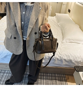 Detail of dark brown vintage bowling bag with gold hardware in a bedroom setting