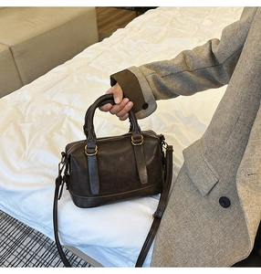 Detail of dark brown leather bowling bag with gold hardware and adjustable strap