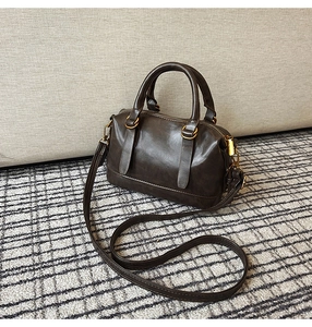 Detail of dark brown vintage bowling bag showing polished PU texture and retro gold hardware