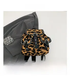 Close-up of leopard print backpack featuring metallic rivets and black leather buckle straps