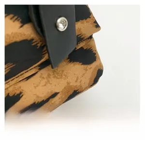 Macro detail of leopard print fabric with black leather trim and silver metal rivet