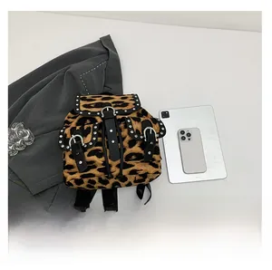 Detailed view of leopard print backpack with silver metal studs and black leather straps