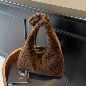 Détail d'un sac cabas à imprimé léopard en fausse fourrure sur une chaise en cuir