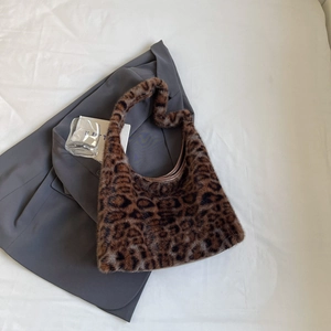 Détail du sac cabas en fausse fourrure léopard posé sur un blazer gris pour l'hiver