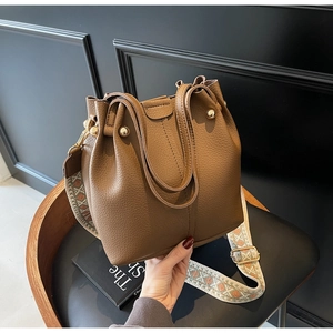 Close-up of brown pebbled leather bucket bag with vintage jacquard wide shoulder strap