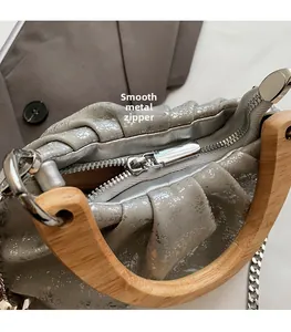 Detail of silver crackle leather bag with smooth metal zipper and wooden handle