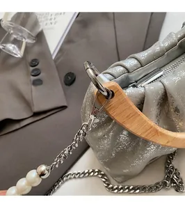 Detail of silver crackle texture handbag with wooden handle and pearl chain strap