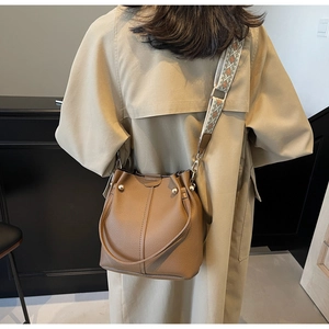 Close-up of brown bucket bag featuring lychee grain leather and ethnic wide strap