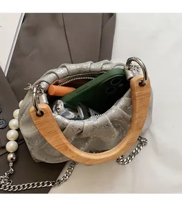 Internal view of silver pleated handbag with wooden handle and large pearl strap detail