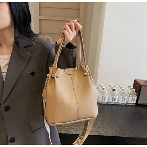 Detail of khaki bucket bag featuring vintage ethnic style wide strap and leather texture