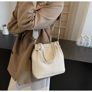Detailed view of cream leather bucket bag with a stylish geometric jacquard strap